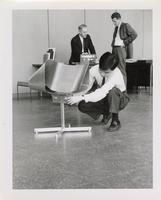 Takatsugu Sugiyama and his Ribbon Chair, Jay Doblin and an unidentified man in the background, S.R. Crown Hall, Illinois Institute of Technology, Chicago, Illinois, ca. 1960